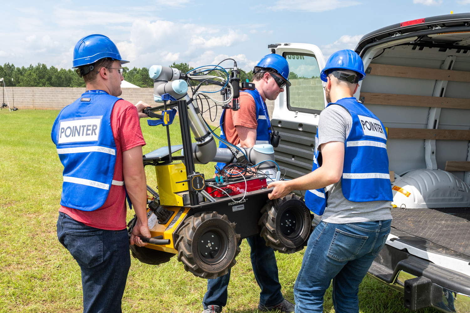 Three team members putting their UGV into a van